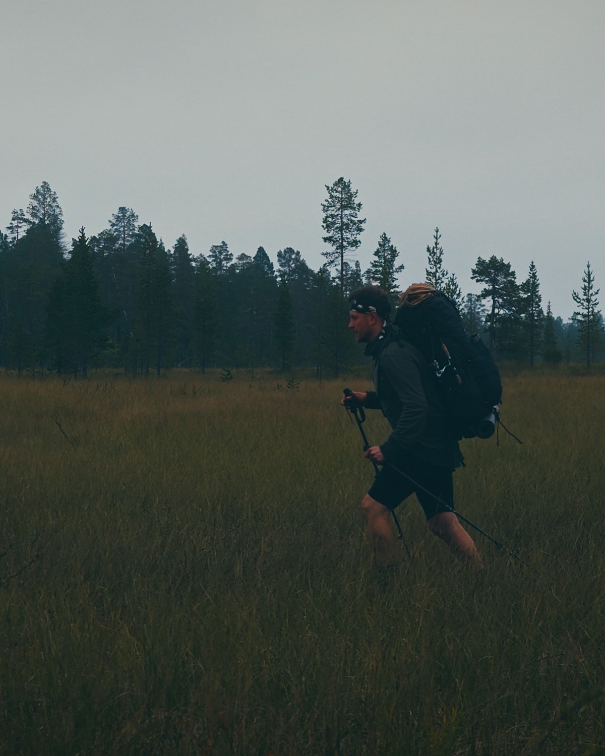 Sakke Raappana ylittää laajaa avosuota rinkka selässä harmaana päivänä Lapissa