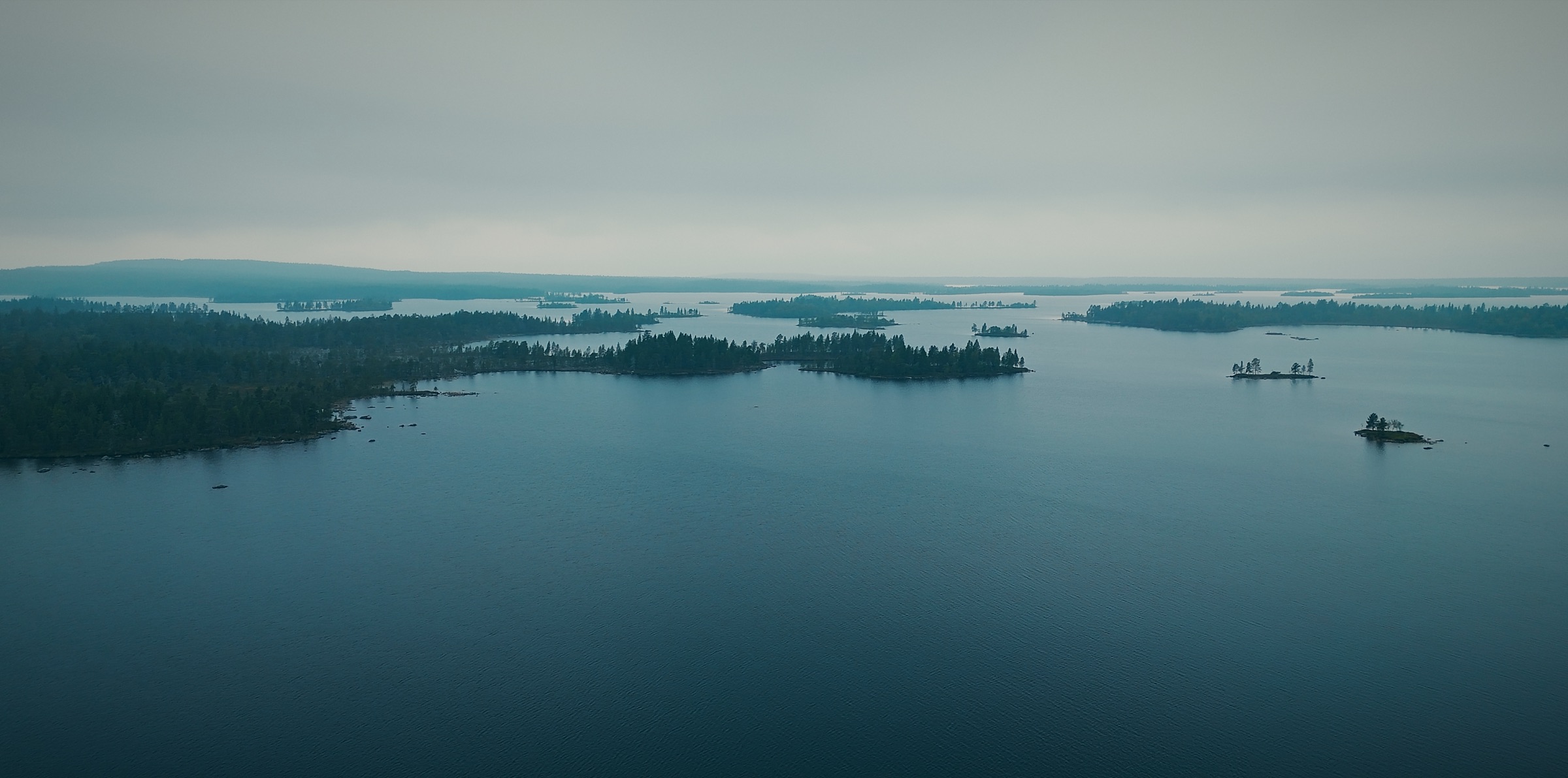 Saarten rikkoma suuri erämaajärvi pilvisenä päivänä Inarissa Lapissa