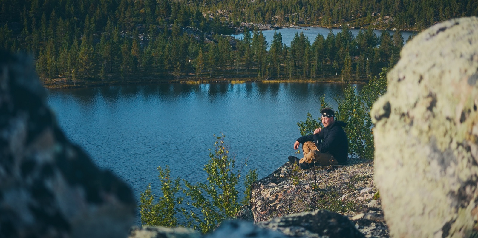 Sakke Raappana istuu kalliolla erämaajärven rannalla Lapissa