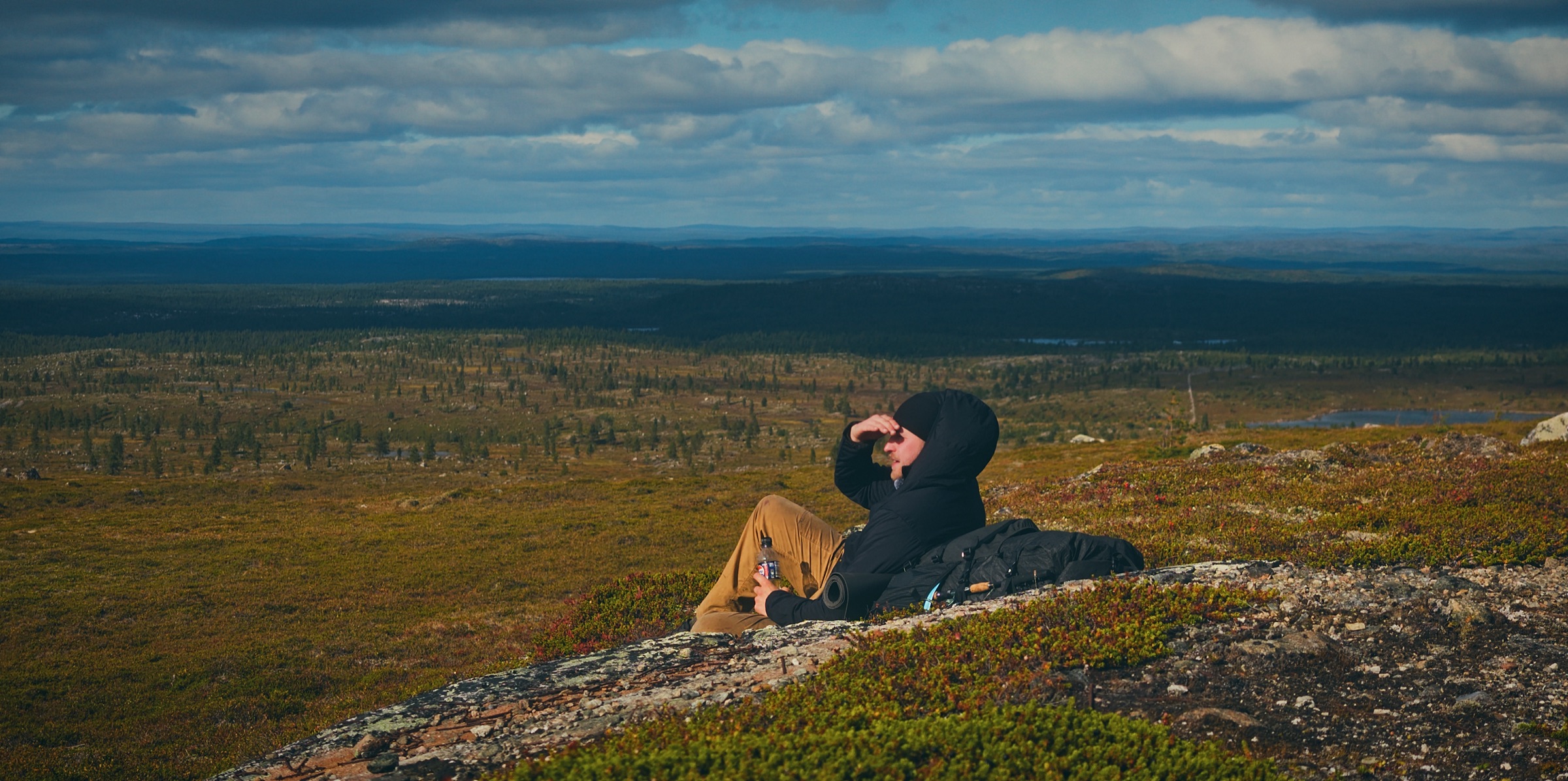 Sakke Raappana lepää kalliolla avaran ylänkömaiseman edessä Vätsärin erämaassa Lapissa