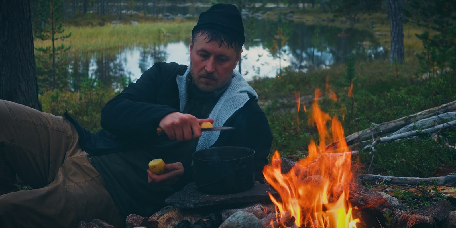 Sakke Raappana kuorii perunaa nuotion äärellä kattila tulella Lapin erämaassa